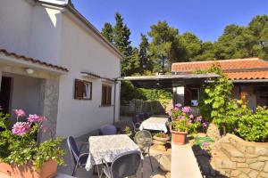 eine Terrasse mit Tischen und Stühlen neben einem Haus in der Unterkunft Apartments in Mali Losinj 14985 in Mali Lošinj