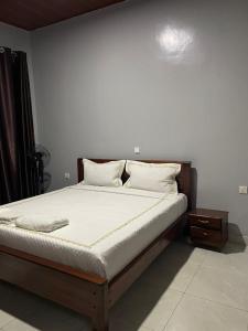 a bed with white sheets and pillows in a bedroom at RITHAN Apartment in Kigali