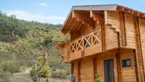 a wooden house with a balcony on the side of it at Cheongdo Ellago Poolvilla Pension in Cheongdo