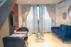 un soggiorno con divano blu e tavolo in vetro di Sky View Condo at Lennox a Trofwi