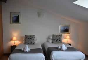 two beds in a room with two lamps at Hôtel Restaurant Petra Cinta in Barcaggio