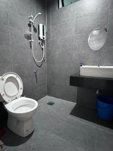 a bathroom with a toilet and a shower and a sink at Zen 66 apartment in Kuching