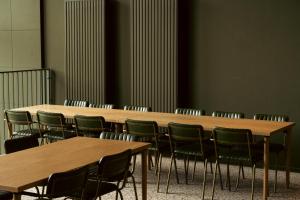a conference room with wooden tables and green chairs at Roberta's Society Aarhus in Aarhus