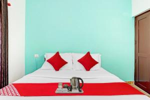 a bed with red pillows and a blender on it at Hotel O Bevis in Trivandrum