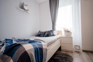 een slaapkamer met een bed met een deken en een raam bij theApartments Manufaktura in Łódź