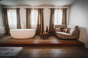 a bathroom with a tub and a chair and a couch at Cangalho Village House Premium in Azueira