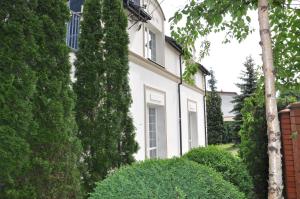 una casa bianca con alberi e cespugli di fronte di BE WELL 3-Rooms Apartment with Parking and Garden a Varsavia