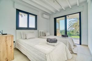 two beds in a room with two windows at Luxury Oasis Villa in Peyia +22 photos