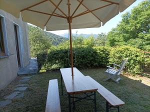 a picnic table with an umbrella and a chair at La casa tra i monti in Ponna Superiore