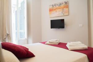 Un dormitorio con una cama con un televisor en la pared. en Four Elements Apartments, en Catania
