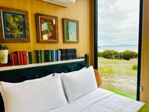 a bedroom with a bed and a book shelf with books at Dunalley Bay Beachfront Retreat by Tiny Away in Murdunna