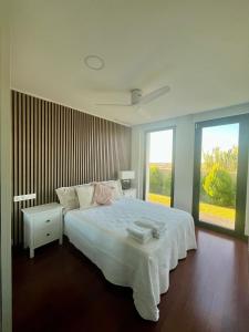 a bedroom with a large white bed and two windows at Puesta de Sol Doñana Adults Only in Sanlúcar de Barrameda