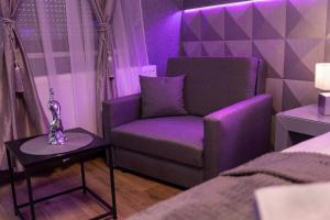 a purple room with a chair and a table at Royal Apartments Gold-Silver Kecskemet in Kecskemét +2 photos