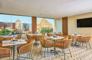 a restaurant with tables and chairs and a view of the pyramids at Cleo Patra Pyramids Tower Inn in Banī Ghālib
