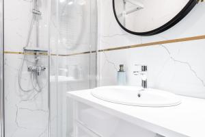 a white bathroom with a sink and a mirror at Business Suites Arkadia by VAYA STAYS in Warsaw +28 photos
