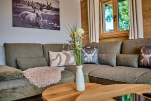 a living room with a couch and a table with flowers at Luxus Chalet Zur Resi in Mauth