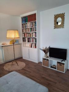 a living room with a tv and a book shelf at ANNA massy tgv in Massy
