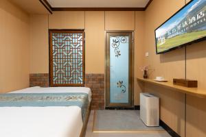 a room with a bed and a television and a door at East Sacred Hotel-Very close to the Drum Tower,The Lama Temple,Houhai Bar Street,Nanluoguxiang,Tiananmen Square and the Forbidden City, and the subway st ation is also very close in Beijing