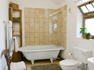 a bathroom with a white tub and a toilet at Cowslip Cottage Ukc1898 in Dogdyke +3 photos