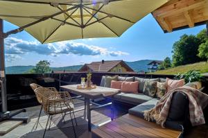 a patio with a couch and a table and an umbrella at Luxus Chalet Zur Resi in Mauth
