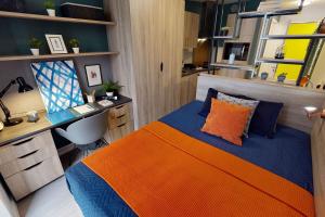 ein Schlafzimmer mit einem orangen und blauen Bett sowie einem Schreibtisch in der Unterkunft Student Only Bronze Studio Plus at Hammersmith Residence in London