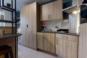 eine Küche mit Holzschränken und einer Spüle in der Unterkunft Student Only Bronze Studio Plus at Hammersmith Residence in London