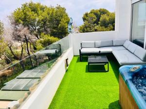 a balcony with a couch and green grass at CHALET MÁGICO en Orihuela Costa in Los Dolses