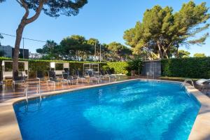 a large swimming pool with chairs and trees at Cabot Tres Torres Apartamentos in Playa de Palma
