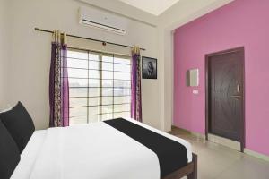 1 dormitorio con 1 cama con paredes de color púrpura y ventana en Super Hotel O Chikmangaluru Near Railway Station, en Chikmagalur