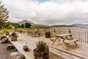 a group of picnic tables on a wooden deck overlooking the water at Blairmore House in Broadford