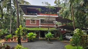 a house with a lot of palm trees in front of it at lakeview homestay in Trikarpur