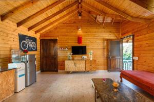 a kitchen and living room with a refrigerator and a couch at The Farmstays CHRPoolGlass RoomsACWi-FiLawn in Hyderabad