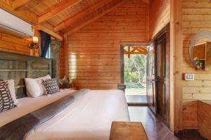 a bedroom in a log cabin with a large bed at The Farmstays CHRPoolGlass RoomsACWi-FiLawn in Hyderabad +29 photos