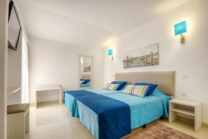 a white bedroom with a blue bed with blue sheets at 3HB Golden Beach in Albufeira