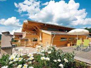 a house with a deck with chairs and an umbrella at Alpin-Chalet Flachau in Flachau +7 photos