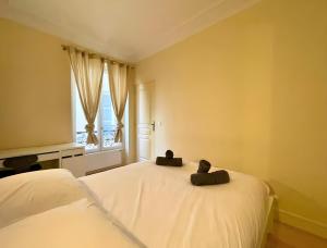 Un dormitorio con una gran cama blanca con ventana. en Cozy appart 15Mn Champs-Élysées, en París