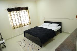 a bedroom with a bed with a black blanket and a window at Agastya FarmsPoolAC4BHKParty Villa25 PaxWifi in Hyderabad