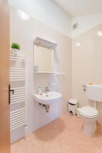 a white bathroom with a sink and a toilet at Hiša Vanda in Dobrovo
