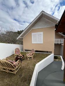 a backyard with two chairs and a house at Casa Cerejeiras in Campos do Jordão