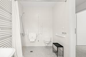 a white bathroom with a toilet and a sink at Gîte Lasauvage 83 in Differdange