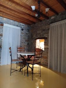 a table and chairs in a room with a stone wall at Volissos Sea View Maisonettes in Volissos
