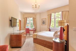 a bedroom with a bed and a desk and windows at Kings Park Hotel in Retford