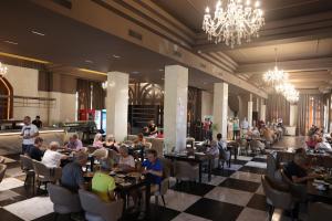 a group of people sitting at tables in a restaurant at Hotel Colombo in Berat
