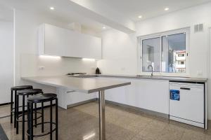 a white kitchen with a counter and stools in it at Hauzify I Apartament Riera in Platja  d'Aro