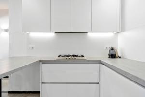 a white kitchen with white cabinets and a stove at Hauzify I Apartament Riera in Platja  d'Aro +20 photos
