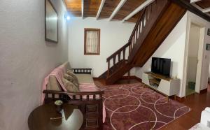 a living room with a couch and a tv at Casa Cerejeiras in Campos do Jordão