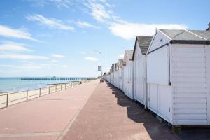 a row of white beach huts on a pier at Maison Studios & Appartements Les 4 Vents in Luc-sur-Mer
