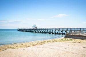 a pier on the ocean with a sandy beach at Maison Studios & Appartements Les 4 Vents in Luc-sur-Mer
