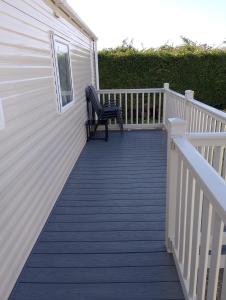 a bench sitting on a deck next to a house at Happy Havan in Great Yarmouth +30 photos