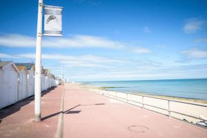 a pier with a banner on a pole next to the ocean at Maison Studios & Appartements Les 4 Vents in Luc-sur-Mer